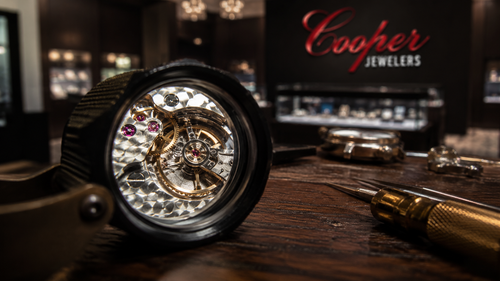 A high contrast macro shot of a jeweler loupe highlighting the intricate balance wheel of a high end Swiss movement for a collector guide on how to choose a luxury watch