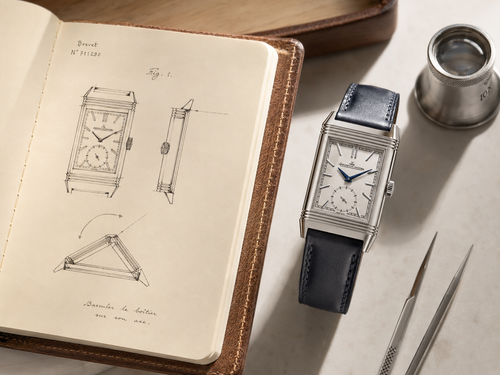 On-wrist lifestyle shot of a stainless steel Jaeger-LeCoultre Reverso watch peeking from a suit cuff in natural light.